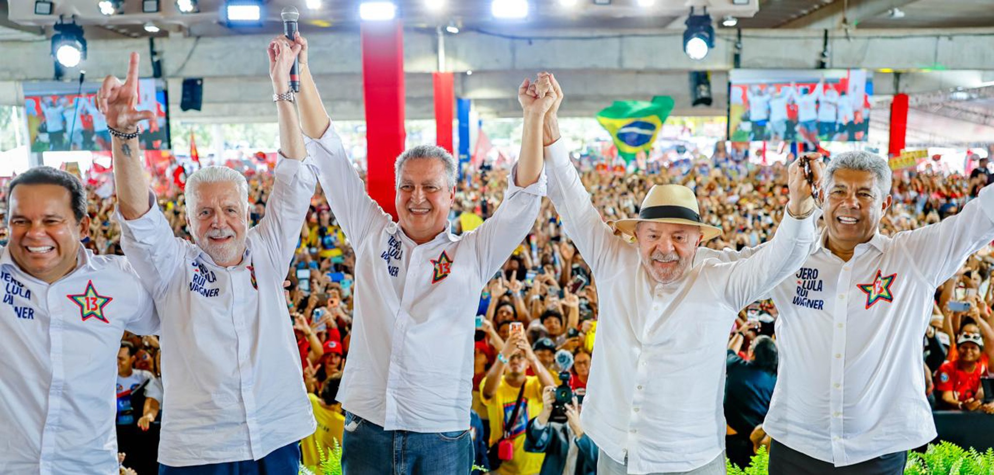 Lula e lideranças políticas da Bahia de mãos dadas e braços erguidos em um ato com apoiadores