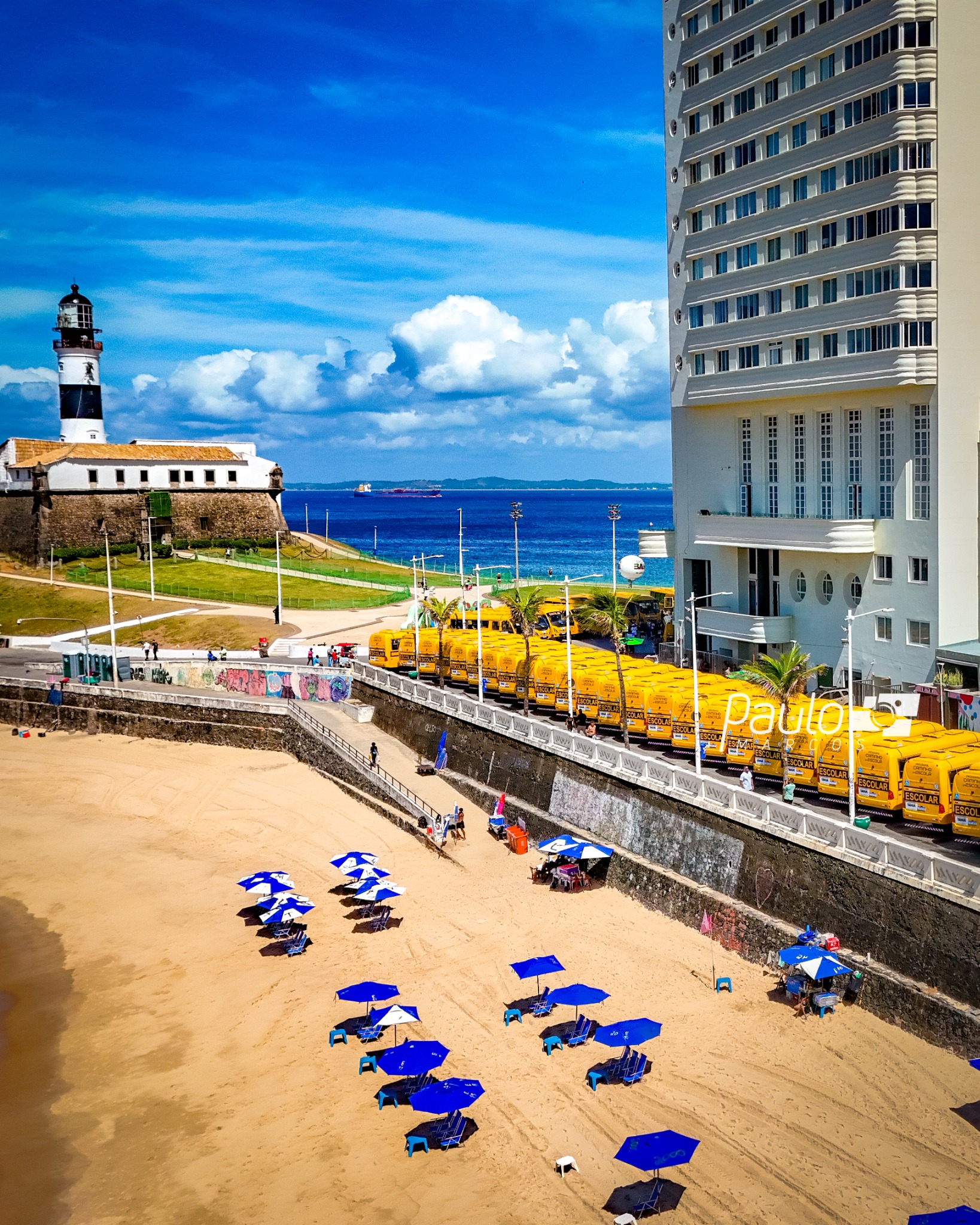 Vista aérea dos ônibus escolares alinhados na orla da Barra