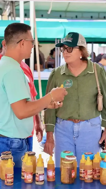 Neusa Cadore conversa com expositor diante de produtos de mel