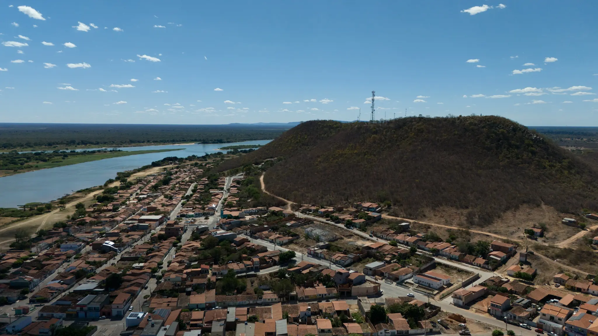 Paisagem que reúne morro, rio e comunidade